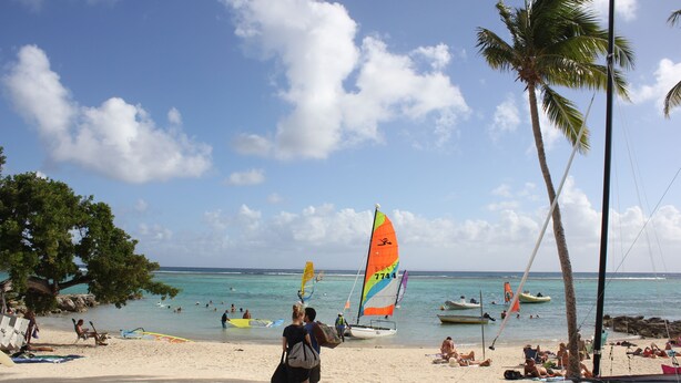 A beach with people, boats, and palm trees. - Duplex apartment located opposite the Golf de Saint-François.  (Saint-François)