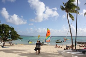 A beach with people, boats, and palm trees. - Duplex apartment located opposite the Golf de Saint-François.  (Saint-François)