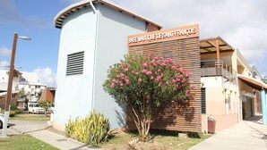 A building with a sign reading "BASE NAUTIQUE DE SAINT-FRANÇOIS" and a small pink flowering tree in front. - Duplex apartment located opposite the Golf de Saint-François.  (Saint-François)