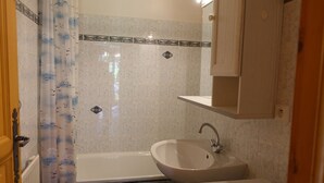 A bathroom with a bathtub, a sink, and a shower curtain. - Quiet apartment for 4, at the foot of the slopes with parking (Arêches-Beaufort)