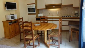 A compact kitchen with a dining table, wooden chairs, a microwave, an oven, and a sink. - Quiet apartment for 4, at the foot of the slopes with parking (Arêches-Beaufort)