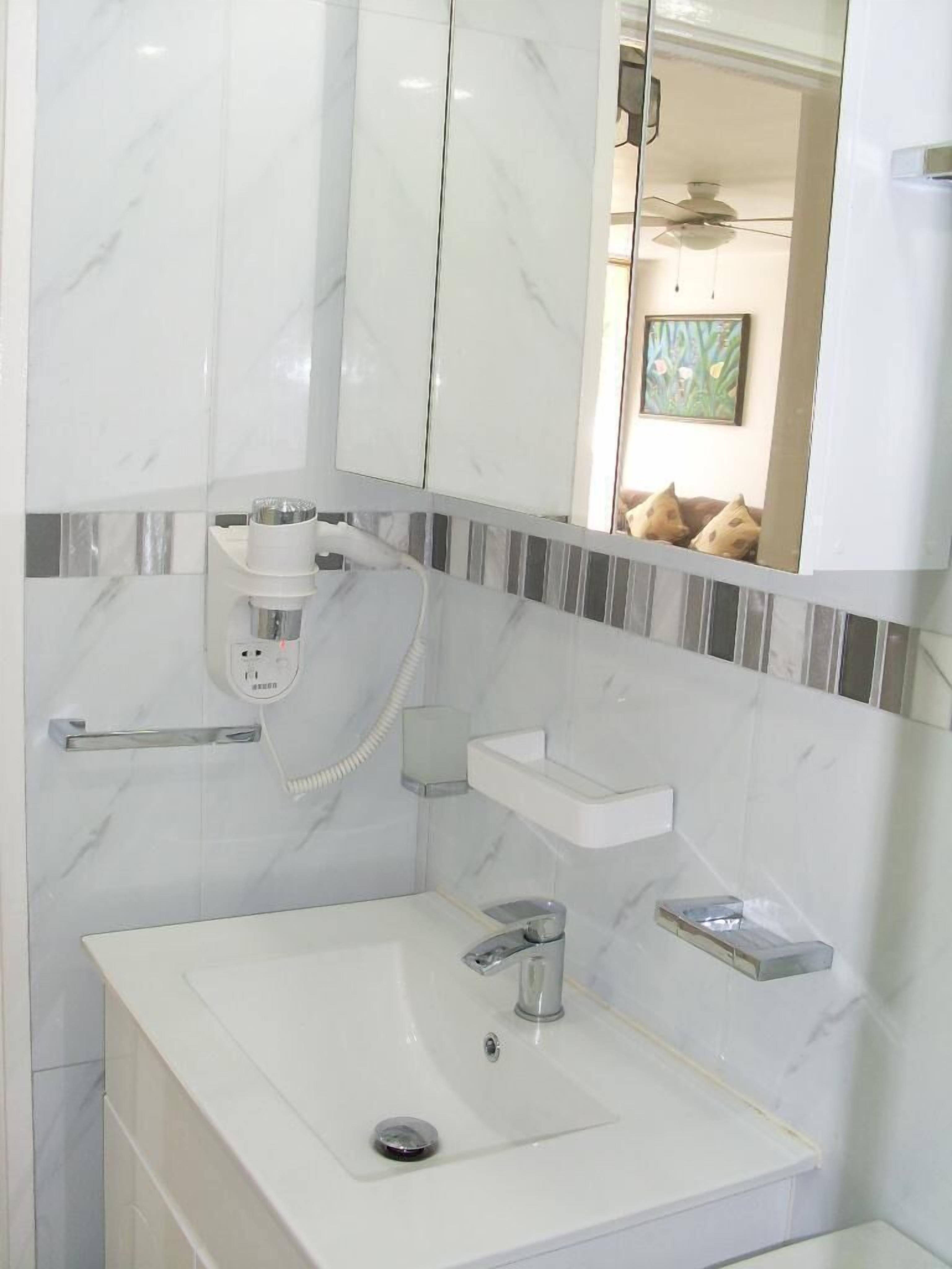 Un bagno con lavandino bianco, uno specchio e un porta asciugamani.