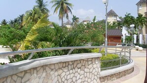 A resort area with a stone wall, palm trees, and a gazebo. - Luxurious beach  front self-catering apartment in the heart of Ocho Rios Jamaica (Ocho Rios)