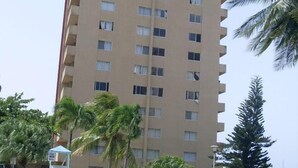 A high-rise hotel with a swimming pool, palm trees, and a lifeguard stand. - Luxurious beach  front self-catering apartment in the heart of Ocho Rios Jamaica (Ocho Rios)