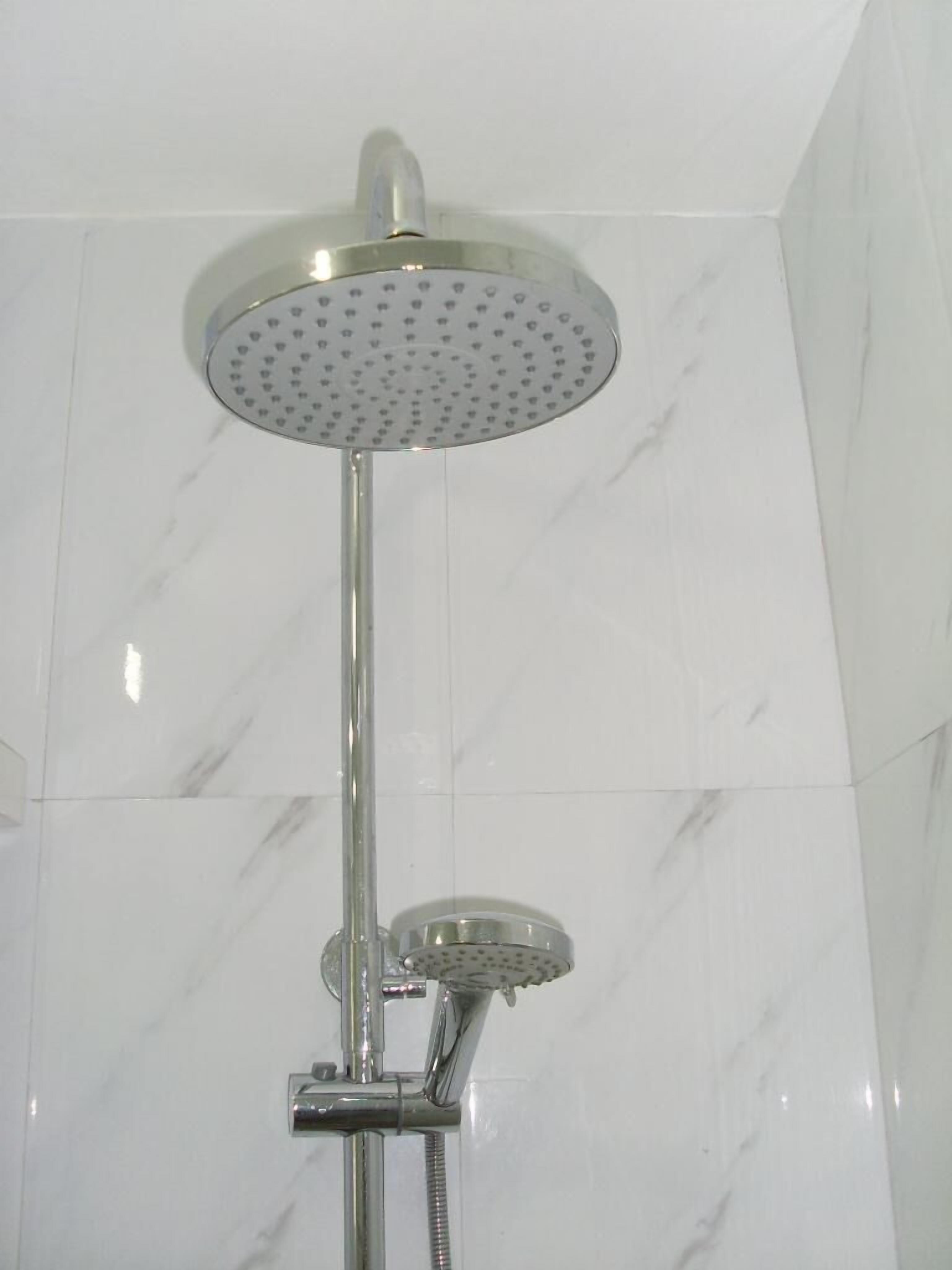 A shower with a round head and a handheld showerhead.