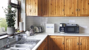 A kitchen with wooden cabinets, a sink, a toaster, a kettle, and a microwave.