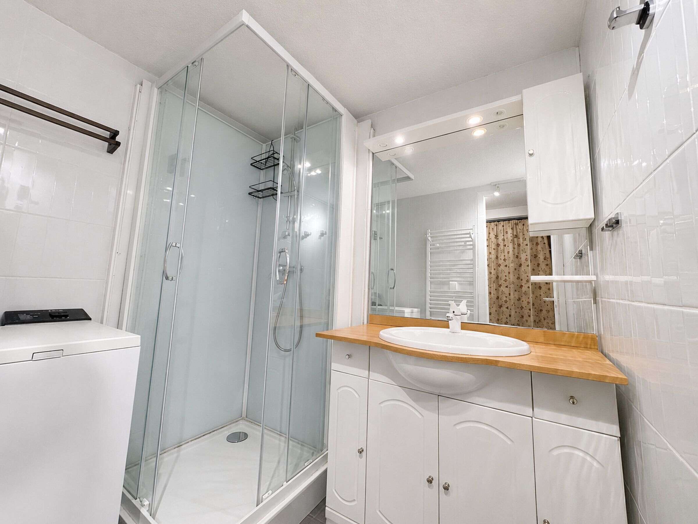 A modern bathroom with a glass-enclosed shower, a white sink, and a wooden countertop.