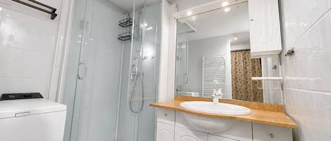 A modern bathroom with a glass-enclosed shower, a white sink, and a wooden countertop.