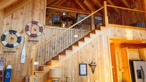 Interior em madeira com escada, paredes de madeira e ventilador de teto.