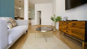 A modern living room with a sofa, a coffee table, a TV, and a wooden dresser. - Tetuán 2D - Two Bedroom Apartment, Sleeps 4 (Sevilla)