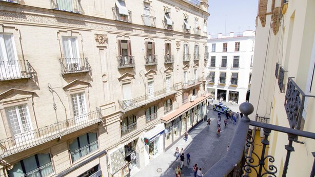 A multi-story building with balconies, a central pedestrian area, and storefronts. - Tetuán 2D - Two Bedroom Apartment, Sleeps 4 (Sevilla)
