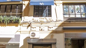 A building facade with ornate architectural details, including a balcony with plants, a sign for 'LOTERIA TETUAN', and a number '3' on the lower part. - Tetuán 2D - Two Bedroom Apartment, Sleeps 4 (Sevilla)