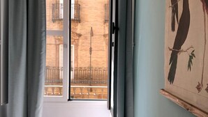 A room with a sliding glass door leading to a balcony with a metal railing and a view of a brick building. - Tetuán 2D - Two Bedroom Apartment, Sleeps 4 (Sevilla)