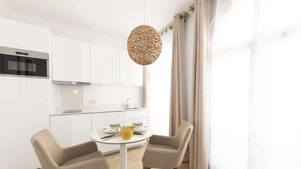 A modern kitchen with white cabinets, a stainless steel oven, and a dining area with two chairs and a table. - Candide, Studio, 2 people (París)