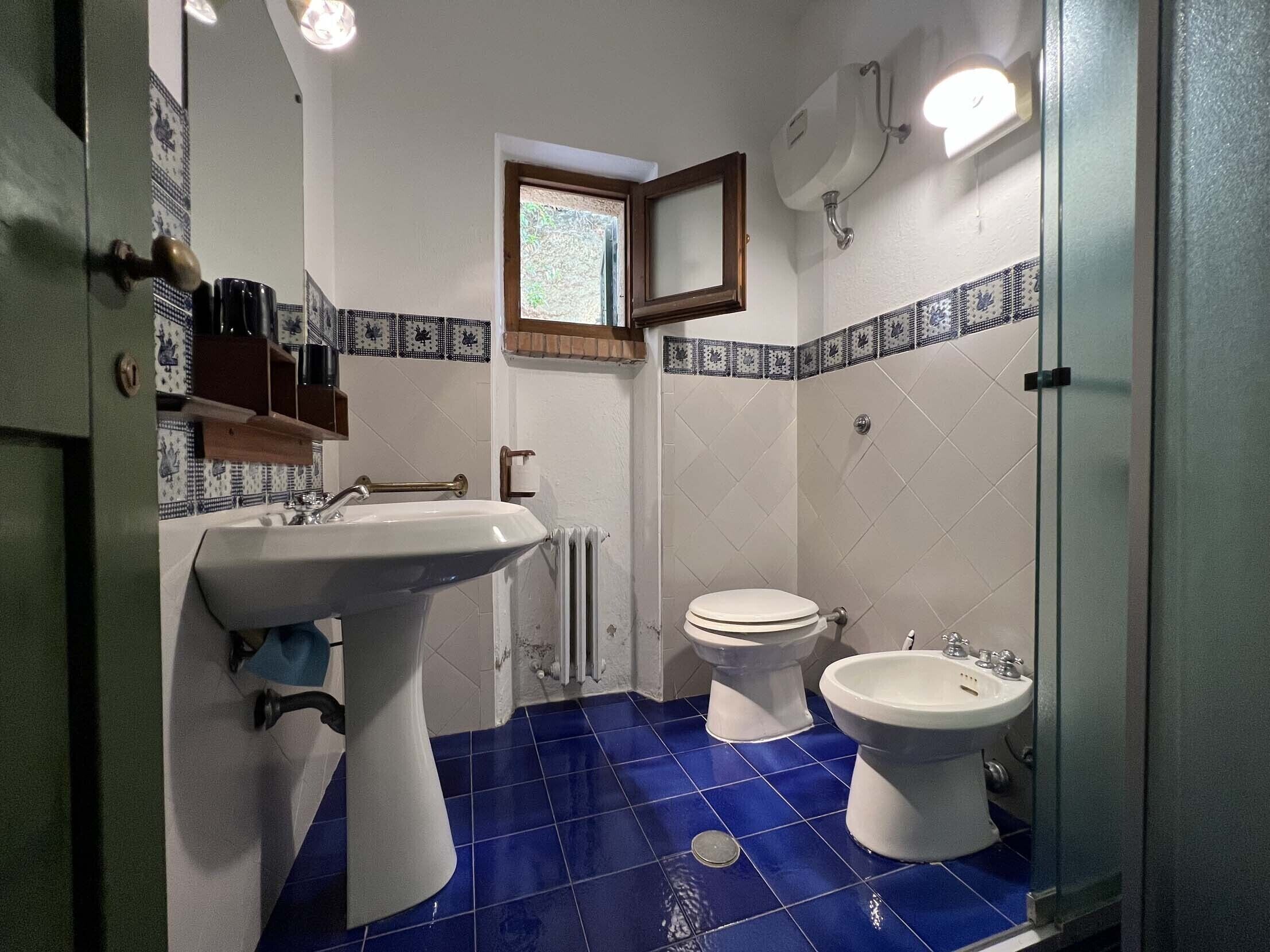 A bathroom with a sink, two toilets, and a bidet.