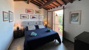 Un dormitorio con cama, mesita de noche, lámpara y puerta que da a un balcón.