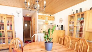 A wooden dining table with chairs, a potted plant, and wooden cabinets with glass doors. - Cozy Mountain Apartment - Sleeps 6, 2 Balconies, Near Slopes - Arêches-Beaufort (Arêches-Beaufort)