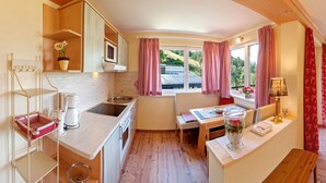 A compact kitchen with wooden cabinets, a sink, and a dining area with a table and bench.