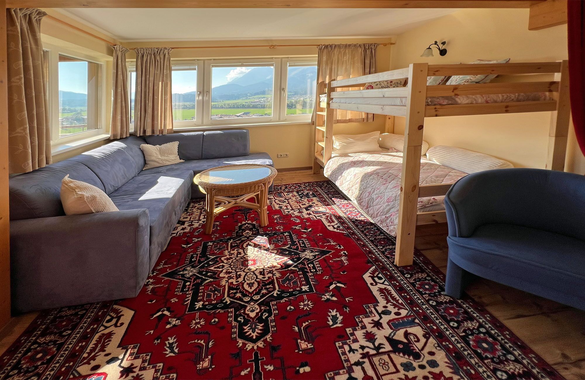 A cozy room with a sofa, a round table, a bunk bed, and a view of the outdoors.