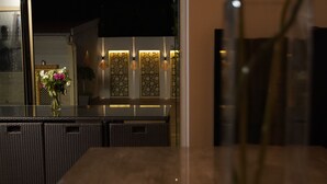 A dining area with a table and chairs, a vase with flowers, and a view of the outside at dusk. - Beautiful holiday home in Paris (Paray-Vieille-Poste)