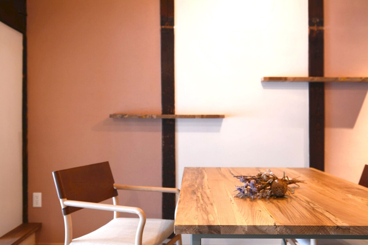 A wooden dining table with a glass top, accompanied by a white chair.