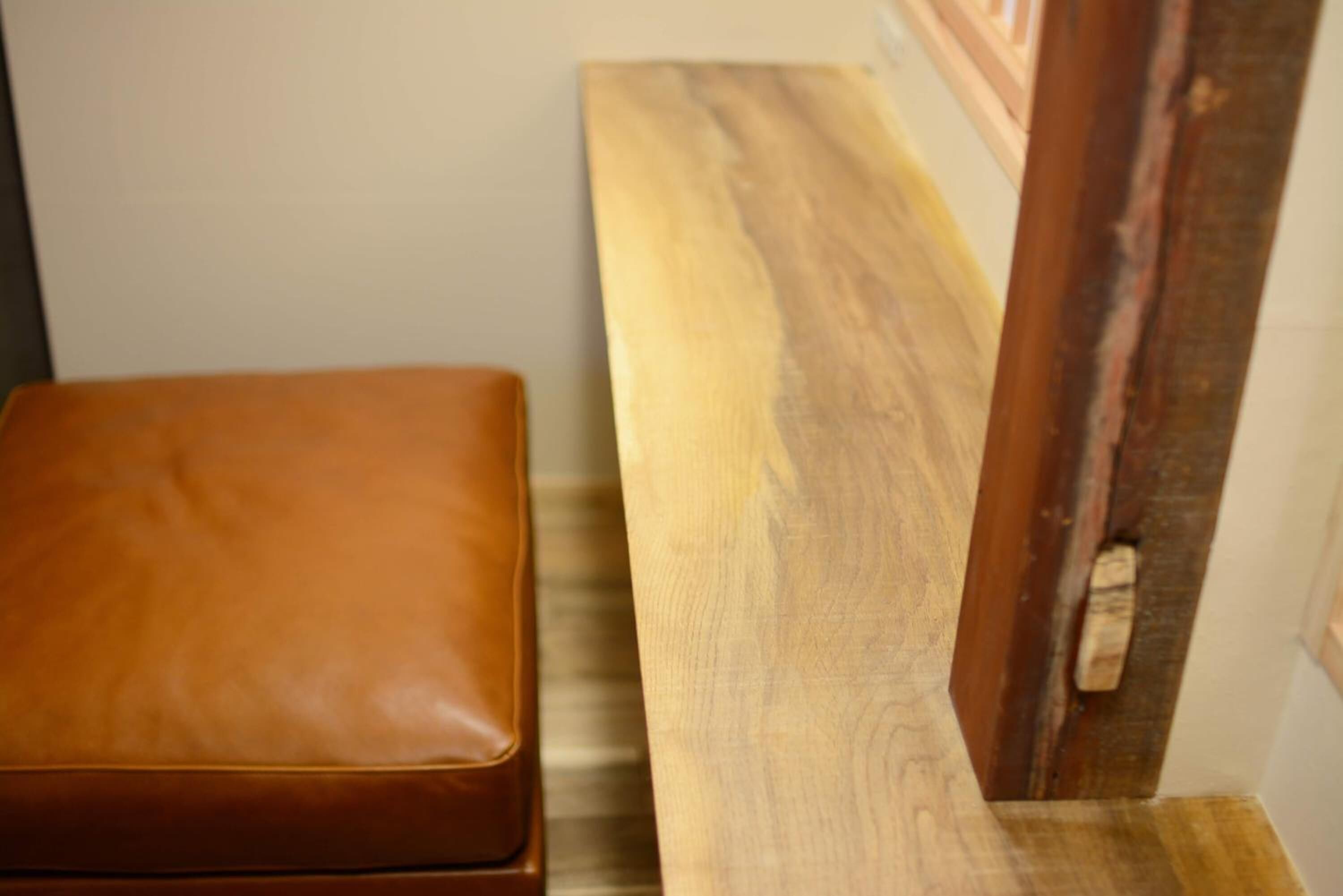 A wooden bench with a leather seat and a wooden table.