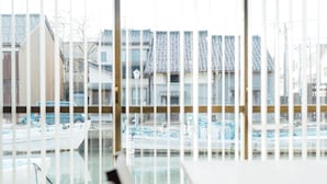A view through a window with vertical blinds, featuring a marina with boats and traditional buildings with tiled roofs. - MINKA Riverside Villas (Imizu)