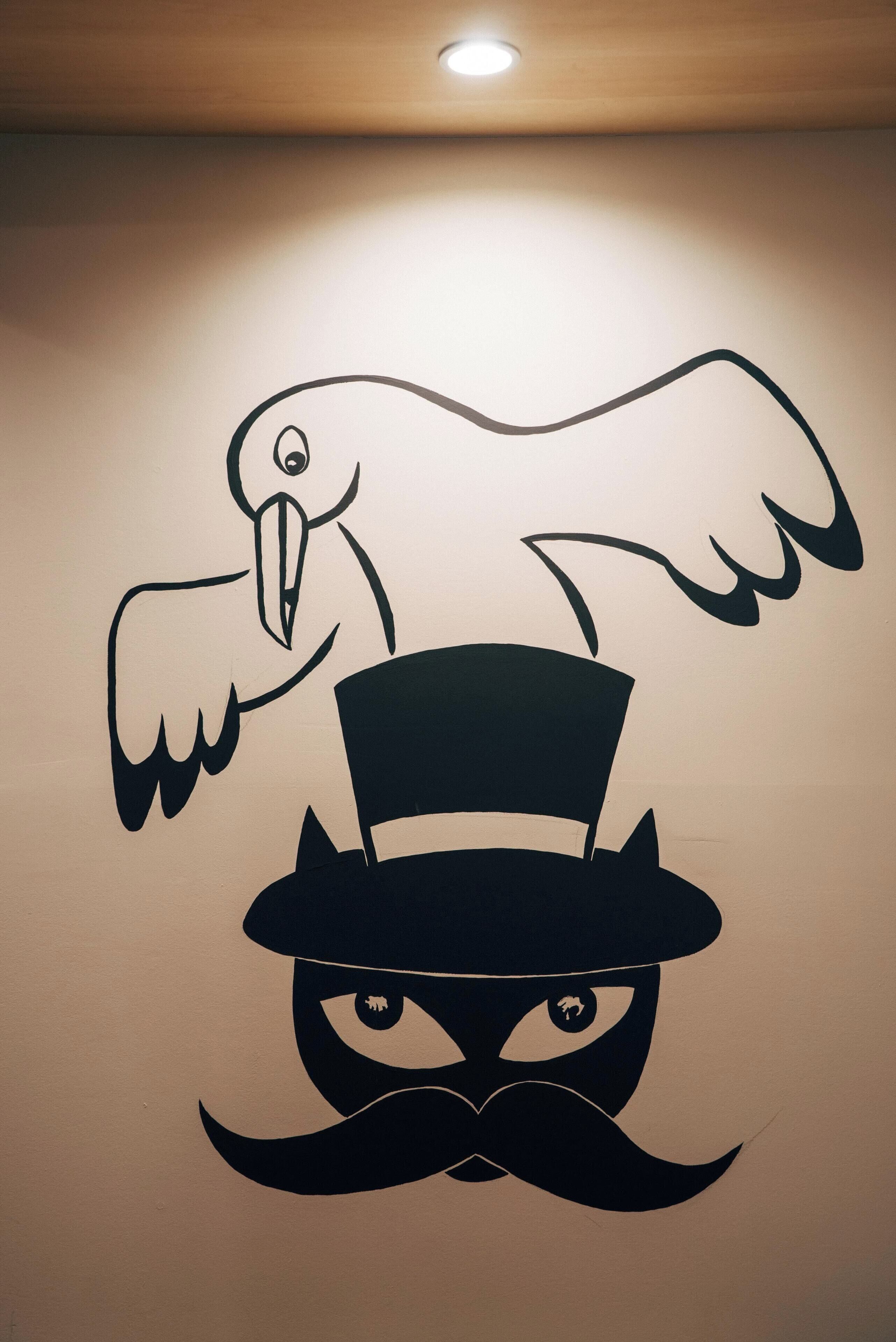 A wall with a stylized bird and a top hat.