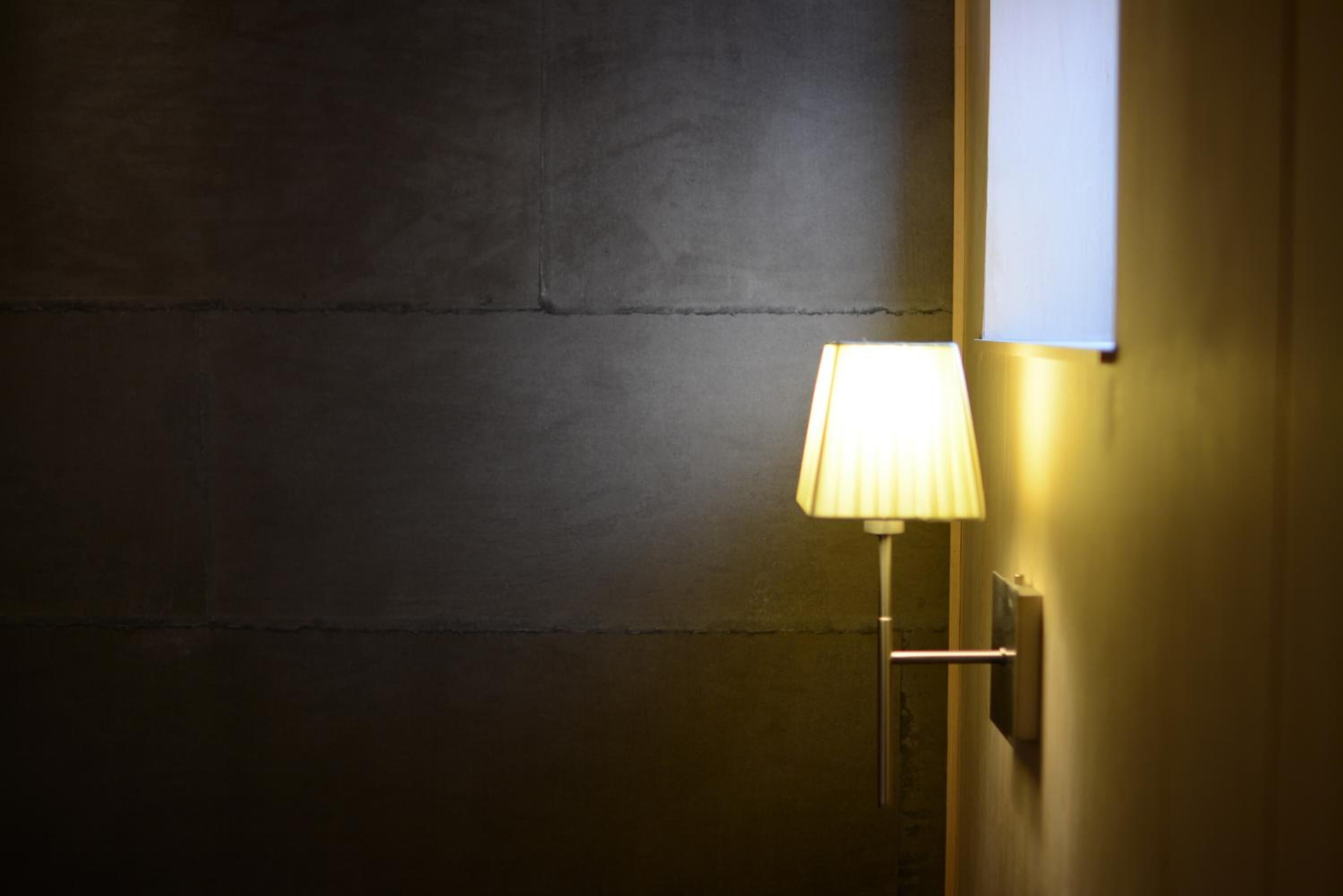 Eine Wand mit strukturierter Oberfläche und einer daran befestigten Wandleuchte.