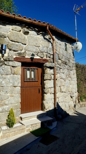 Traditional stone building with a wooden door and metal grill, offering a charming entrance.