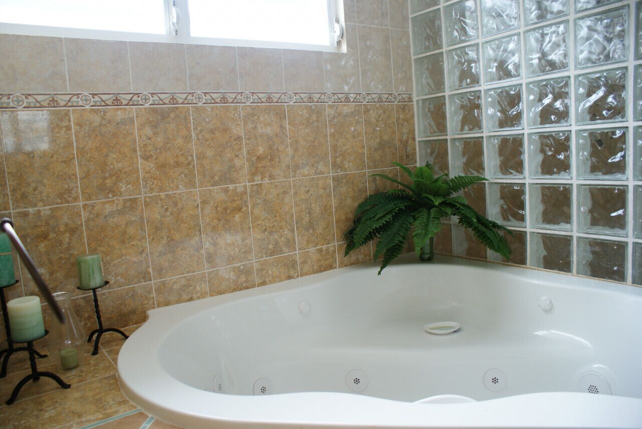 Un baño con una bañera independiente, una planta en maceta y un ventanal.