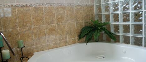 Un baño con una bañera independiente, una planta en maceta y un ventanal.