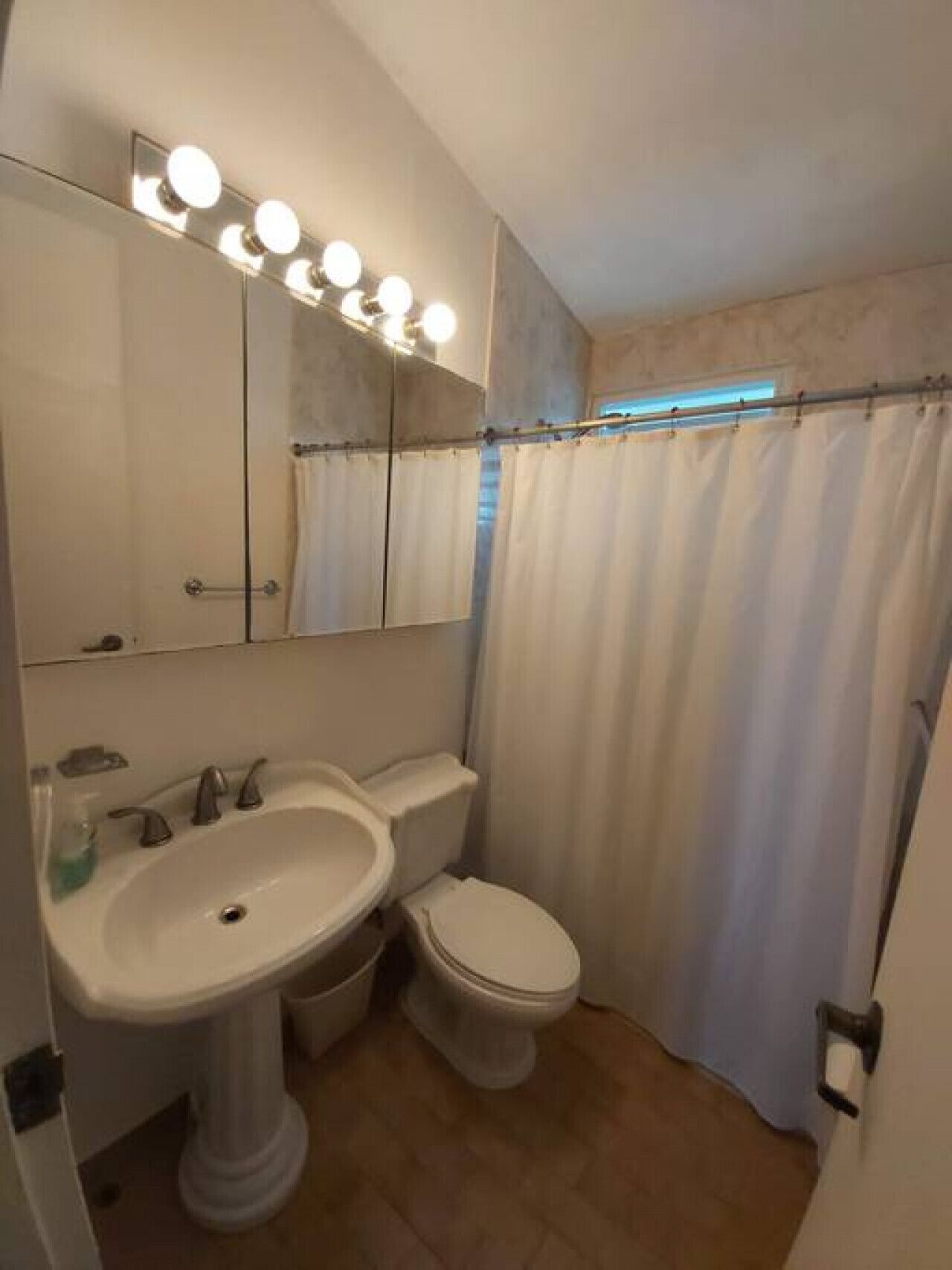 A bathroom with a pedestal sink, a toilet, and a shower curtain.