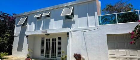 Un bâtiment à deux étages doté d’un garage, de panneaux solaires et de plantes en pot.