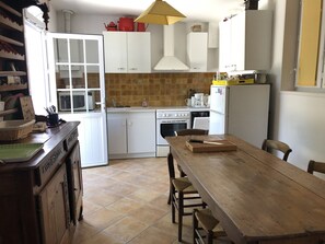A kitchen with white cabinets, a wooden table, and a tiled backsplash.
