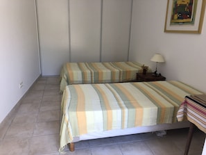 Ein Zimmer mit zwei Betten, einem Nachttisch, einer Lampe und einem gerahmten Bild an der Wand.