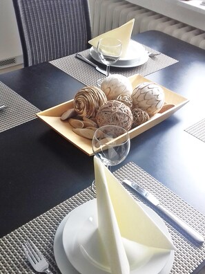 Una mesa de comedor con un plato de comida, un vaso de agua y una servilleta.
