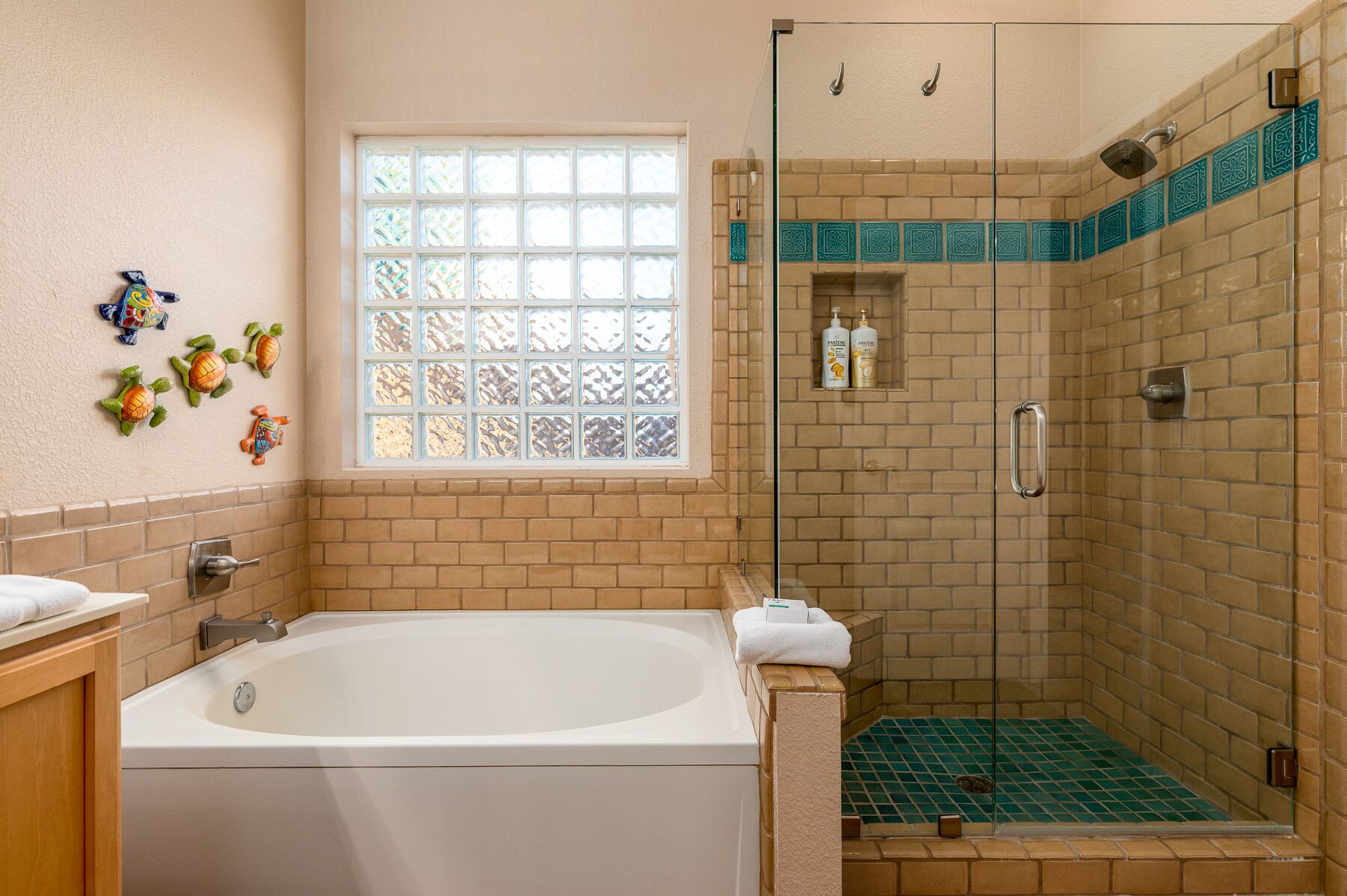 Un bagno con una vasca, una doccia con porta in vetro, una finestra con vetro decorativo e un muro a mattoni.