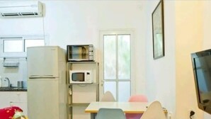 A small kitchen with a refrigerator, microwave, and a window. - Cozy 2 Bedroom Apartment by The Beach (Tel Aviv)
