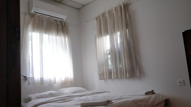 A room with two beds, white curtains, an air conditioning unit, and a window. - Cozy 2 Bedroom Apartment by The Beach (Tel Aviv)