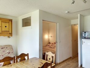 Een compacte keuken met houten meubels, een eettafel en een koelkast.