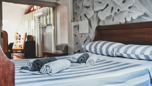 Ein Hotelzimmer mit einem Bett, ausgestattet mit gestreifter Bettwäsche, zusammengerollten Handtüchern und einem dekorativen Kopfteil.