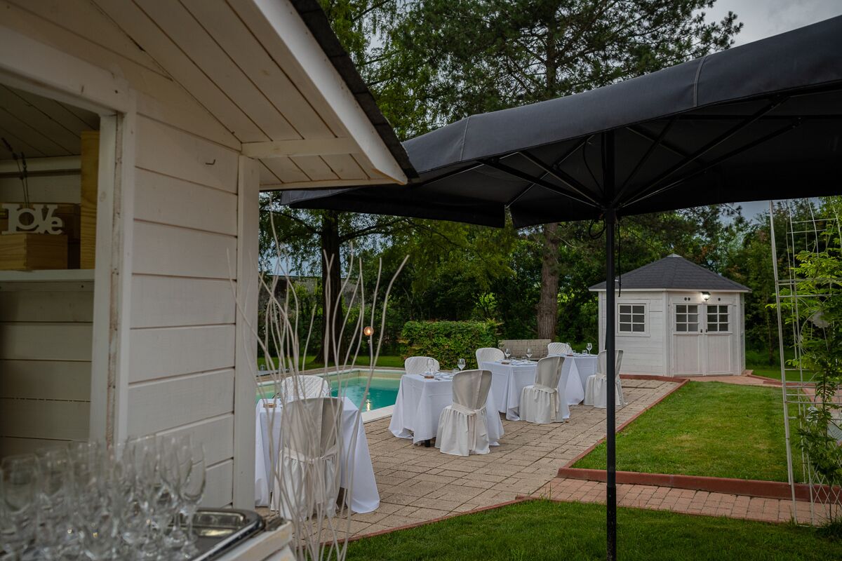 Eine Außenpatio mit Tischen, Stühlen, einem Pool und einer kleinen Gartenhütte.