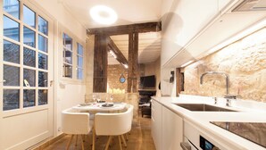 Una cocina moderna con una pared de piedra, una zona de comedor con dos sillas y un ventanal grande.