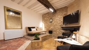 Una sala de estar con pared de piedra, chimenea, sofá, mesa de centro y televisión.