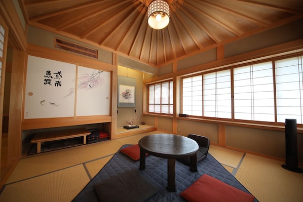Une pièce de style japonais traditionnel, avec un sol recouvert de tatamis, une table basse et des portes coulissantes ornées de calligraphies.