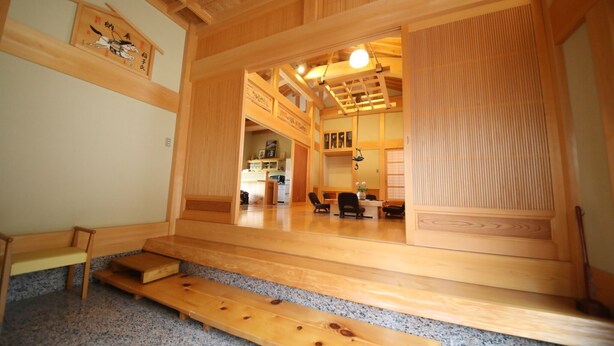 Een traditionele Japanse kamer met tatami vloerbedekking, een lage houten bank en een schuifdeur naar een keuken.