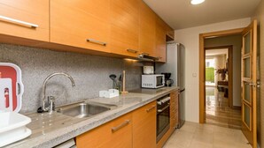A modern kitchen with wooden cabinets, a granite countertop, stainless steel sink, and a built-in oven.