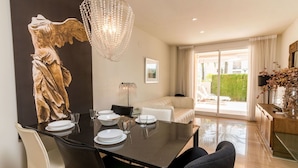 A dining area with a table set for four, a chandelier, and a statue on the wall.
