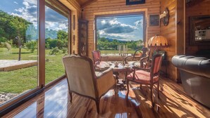 A wooden cabin interior with a dining table set for four, surrounded by chairs, and a leather sofa. - Lovely home in Gospic (Gospic)